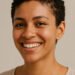 Mujer latina generada con IA con cabello rizado corto y natural tras el big chop, sonriendo con seguridad y orgullo