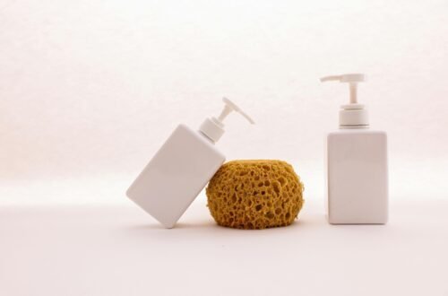 Two white soap dispensers with a sponge on top