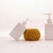 Two white soap dispensers with a sponge on top