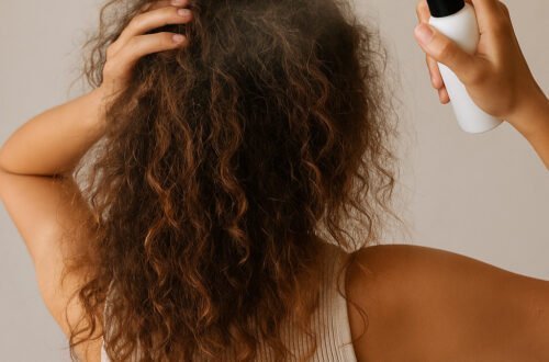imagen generada por ia Melena rizada con frizz mientras una mujer aplica spray con la mano, ejemplo de rutina rápida para definir rizos en poco tiempo