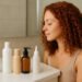 imagen generada por IA de mujer con rizos color cobre observando productos para cabello rizado en el baño, para ranking de mejores productos método Curly