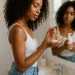 imagen generada por IA de mujer con cabello rizado tipo 3B aplicando producto apto para el metodo curly en el baño