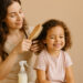 imagen generada por IA – madre enseñando como desenradar con cuidado el cabello rizado de su hija pequeña