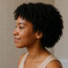 imagen generada por IA mujer con cabello tipo 4B en perfil, en baño con azulejos beige, como parte de una rutina curly hidratante